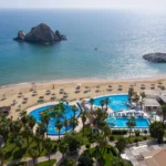 Aerial view of a luxury beach resort with swimming pools, water slides, and an ocean island