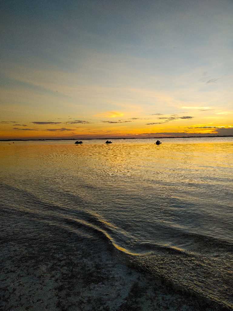 Peaceful sunset casting golden reflections on calm ocean water in Pingwe, Zanzibar