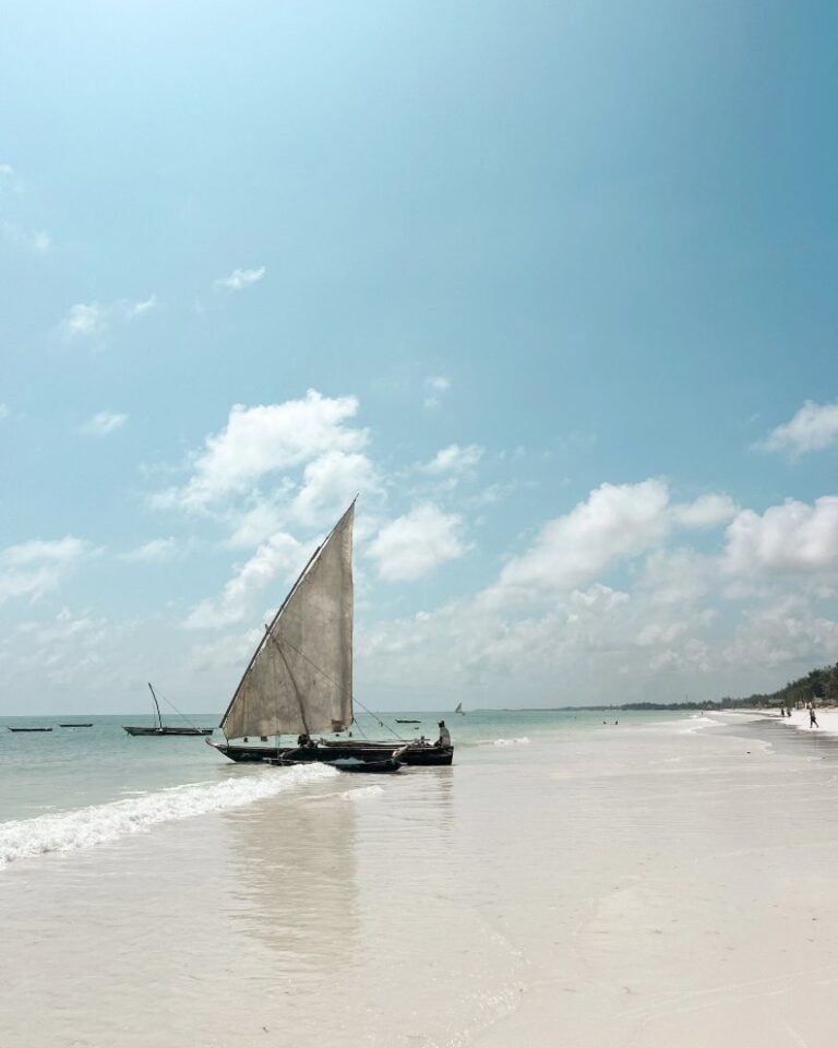 Traditional dhow boat floating in shallow ocean water along Mtende Beach in Zanzibar